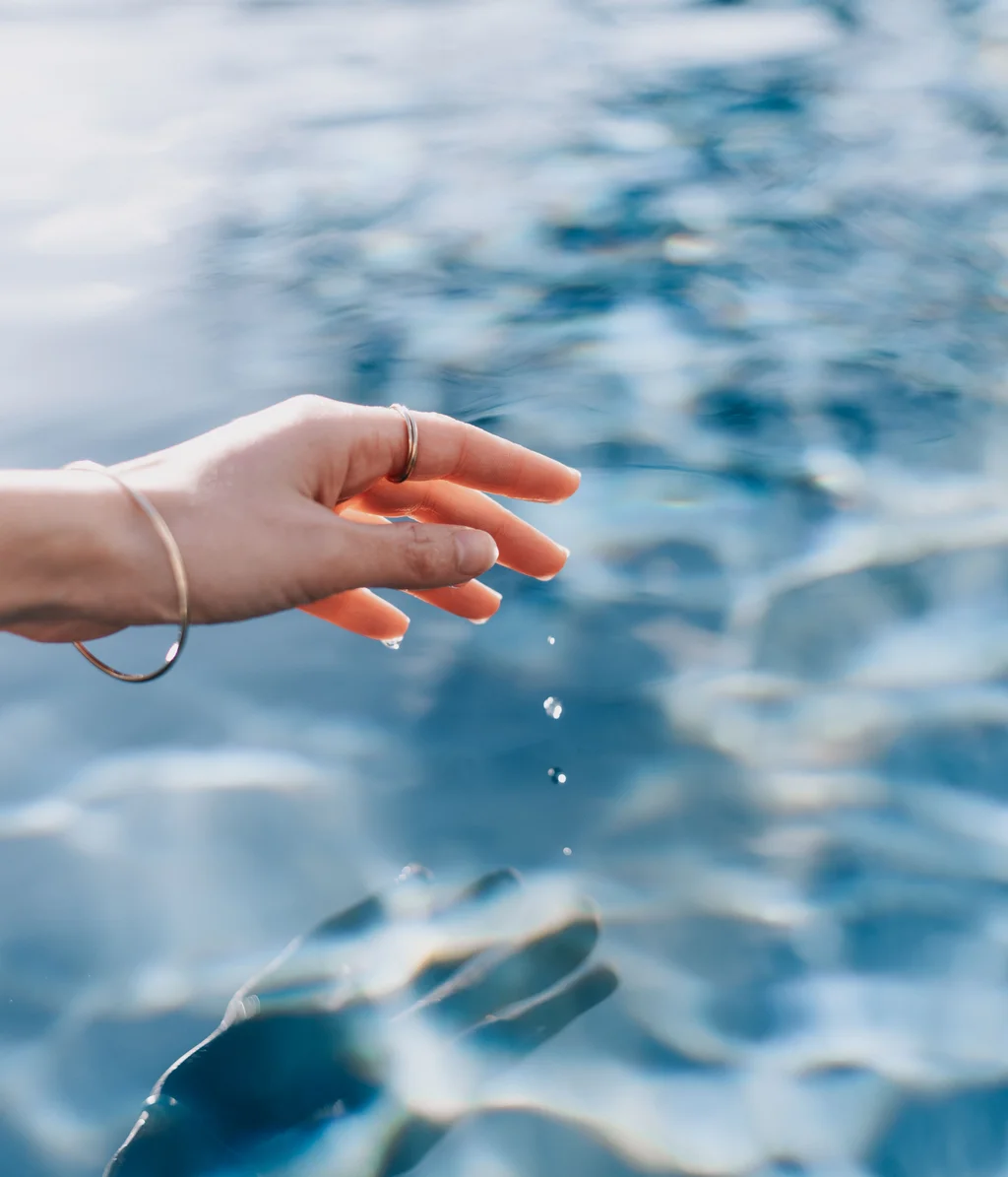 Cubea | Chalet-Apartments in Bodenmais für hohe Ansprüche Hand berührt Wasseroberfläche mit fallenden Wassertropfen