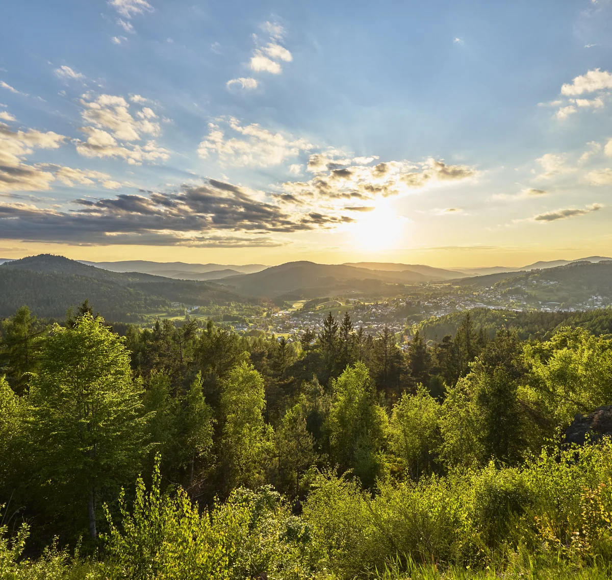 Cubea | Chalet-Apartments in Bodenmais für hohe Ansprüche Sonnenuntergang über bewaldeten Hügeln und einem Tal mit Dorf