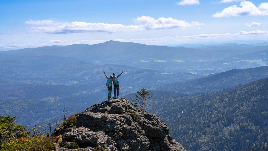 Cubea – privater Rückzugsort im Bayerischen Wald Zwei Wanderer auf Felsen mit Aussicht auf bewaldete Berge und blauen Himmel