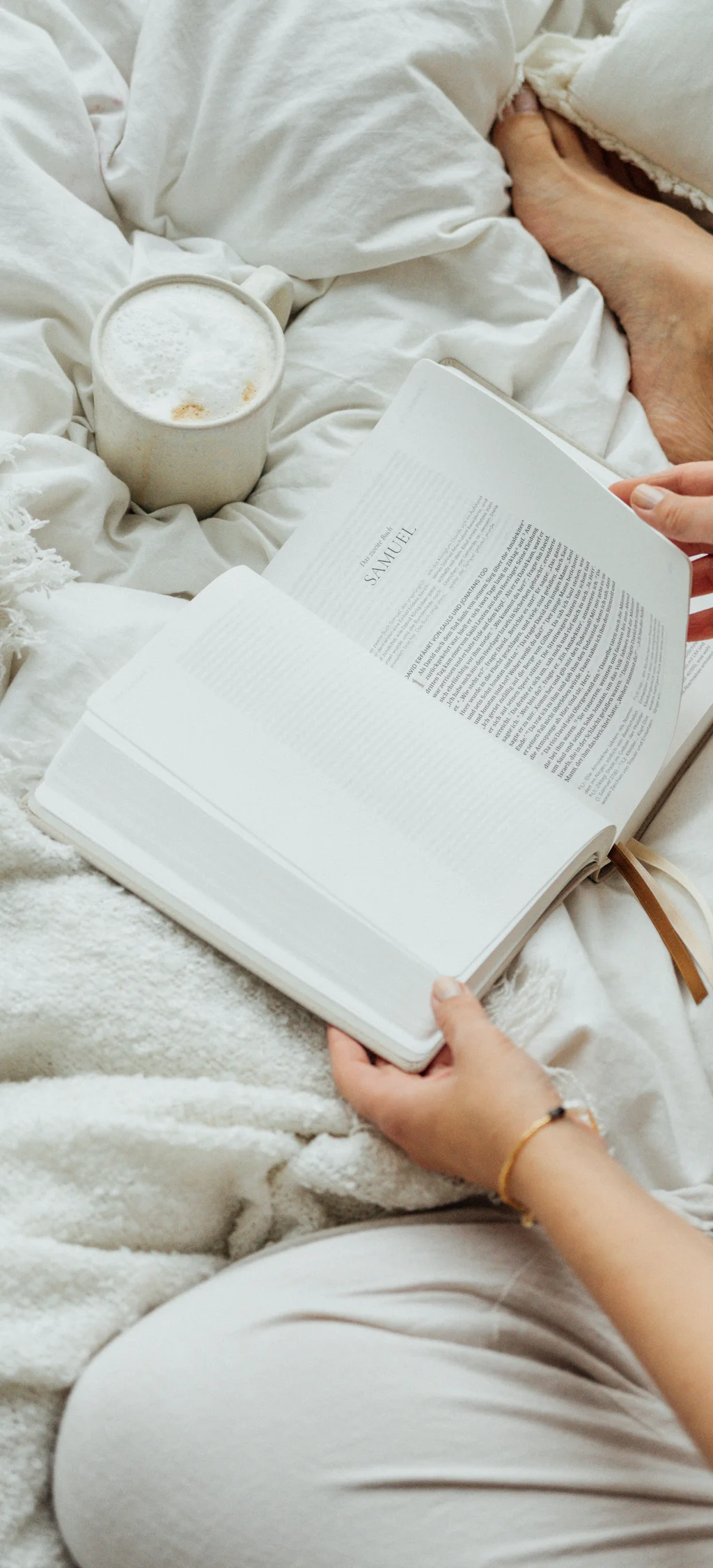 Cubea | Chalet-Apartments in Bodenmais für hohe Ansprüche Person liest Buch im Bett mit Kaffee auf weißer Decke