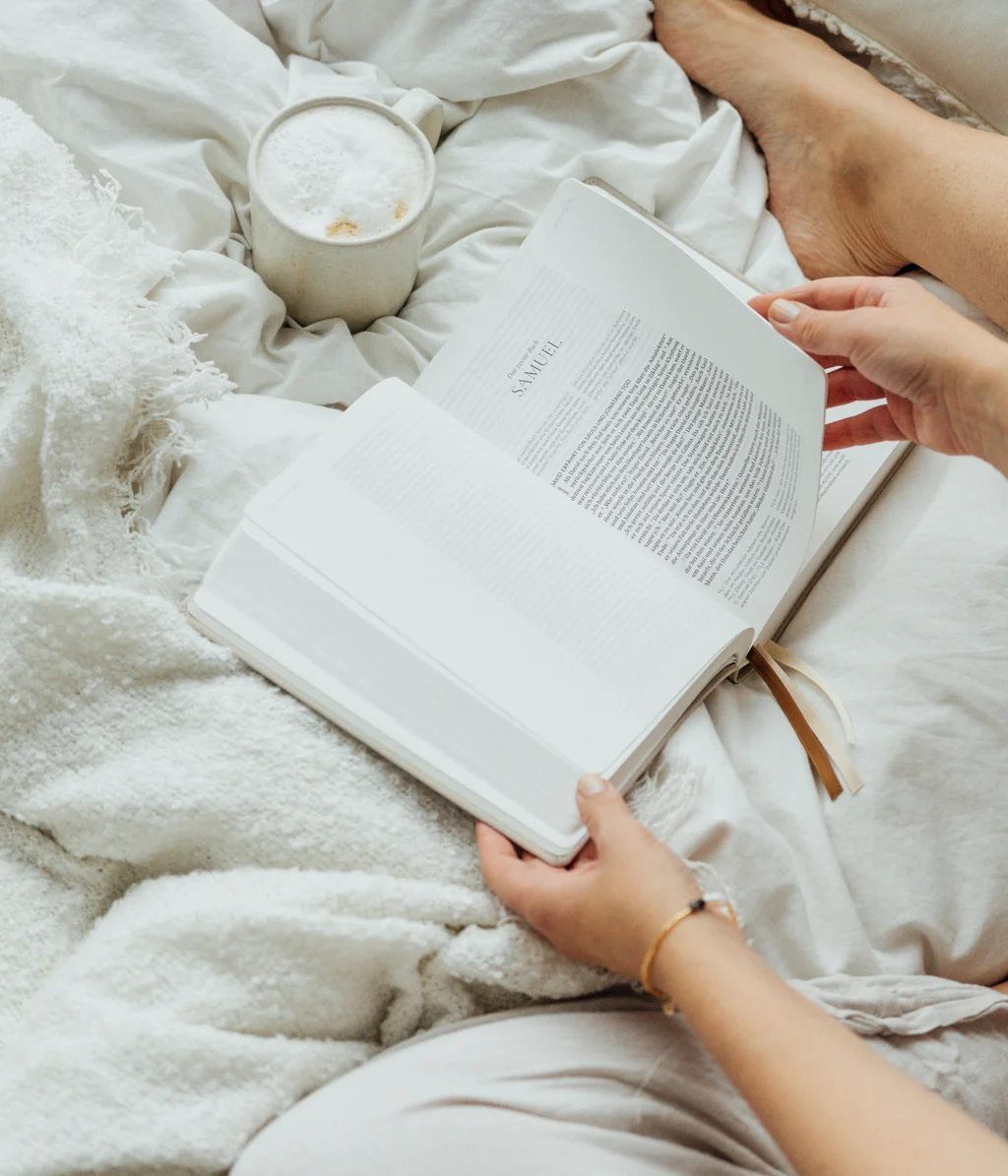 Cubea | Chalet-Apartments in Bodenmais für hohe Ansprüche Person liest Buch im Bett mit Kaffee auf weißer Decke