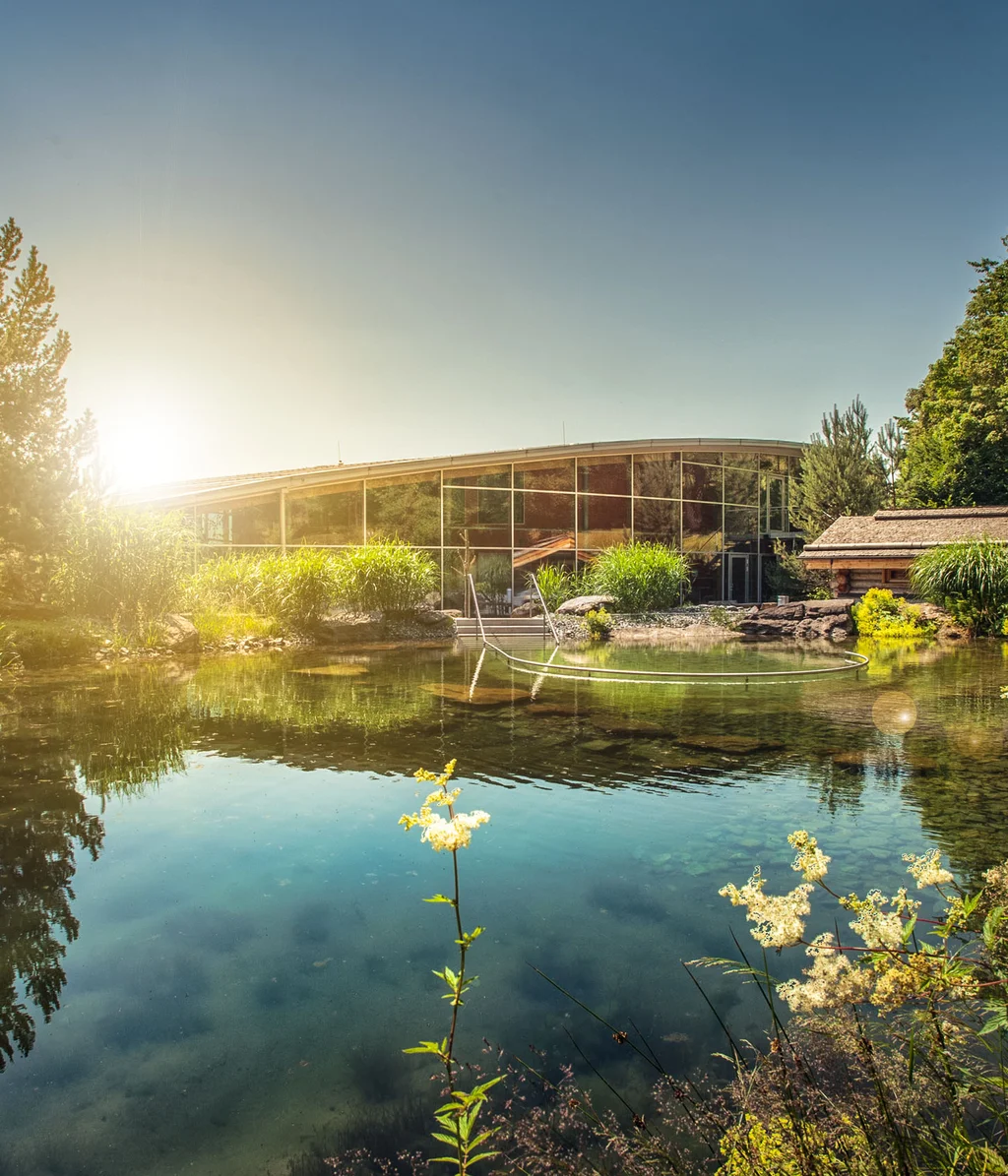 Cubea | Chalet-Apartments in Bodenmais für hohe Ansprüche Sonniger Teich mit Spiegelung und modernem Gebäude im Hintergrund