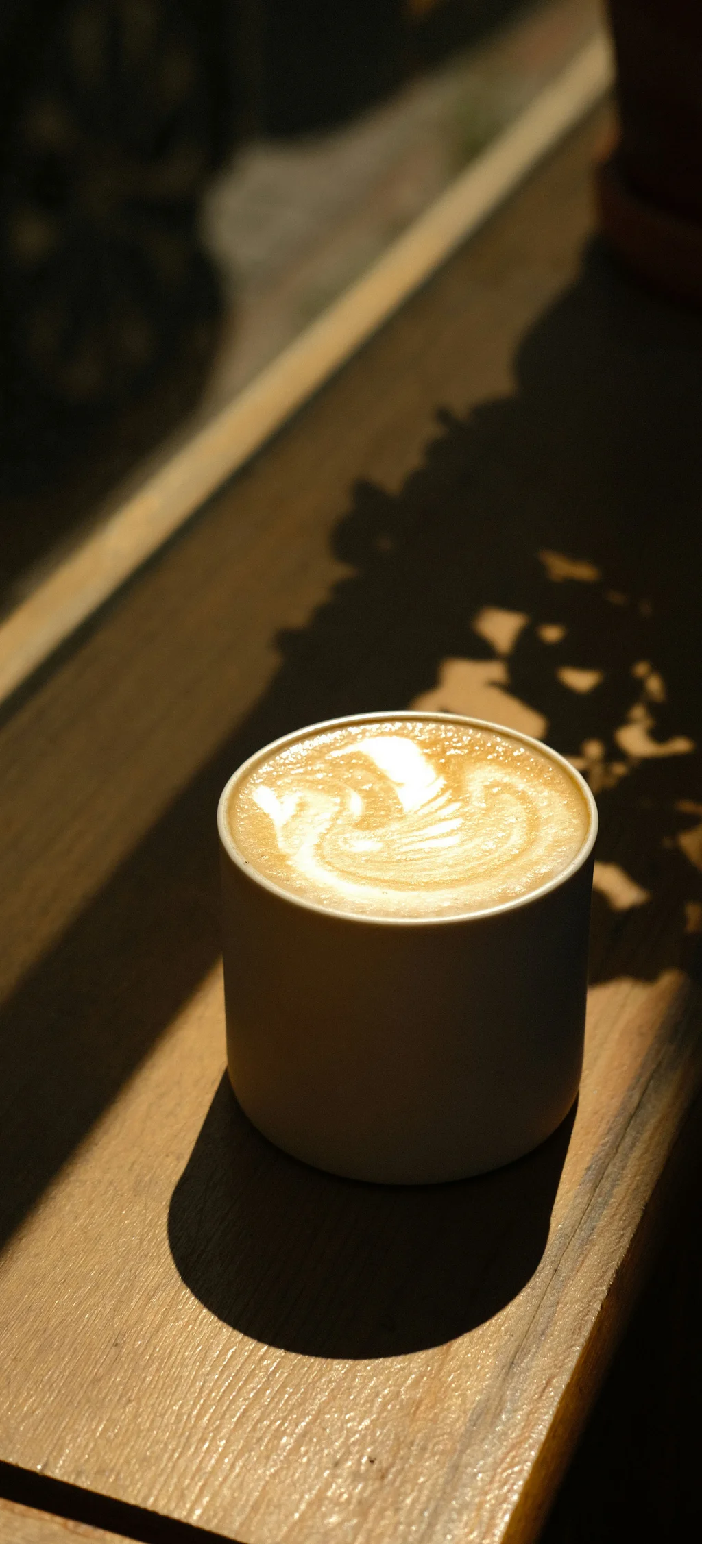 Cubea | Chalet-Apartments in Bodenmais für hohe Ansprüche Tasse Kaffee mit Milchschaum und Latte Art auf Holzfensterbank im Sonnenlicht